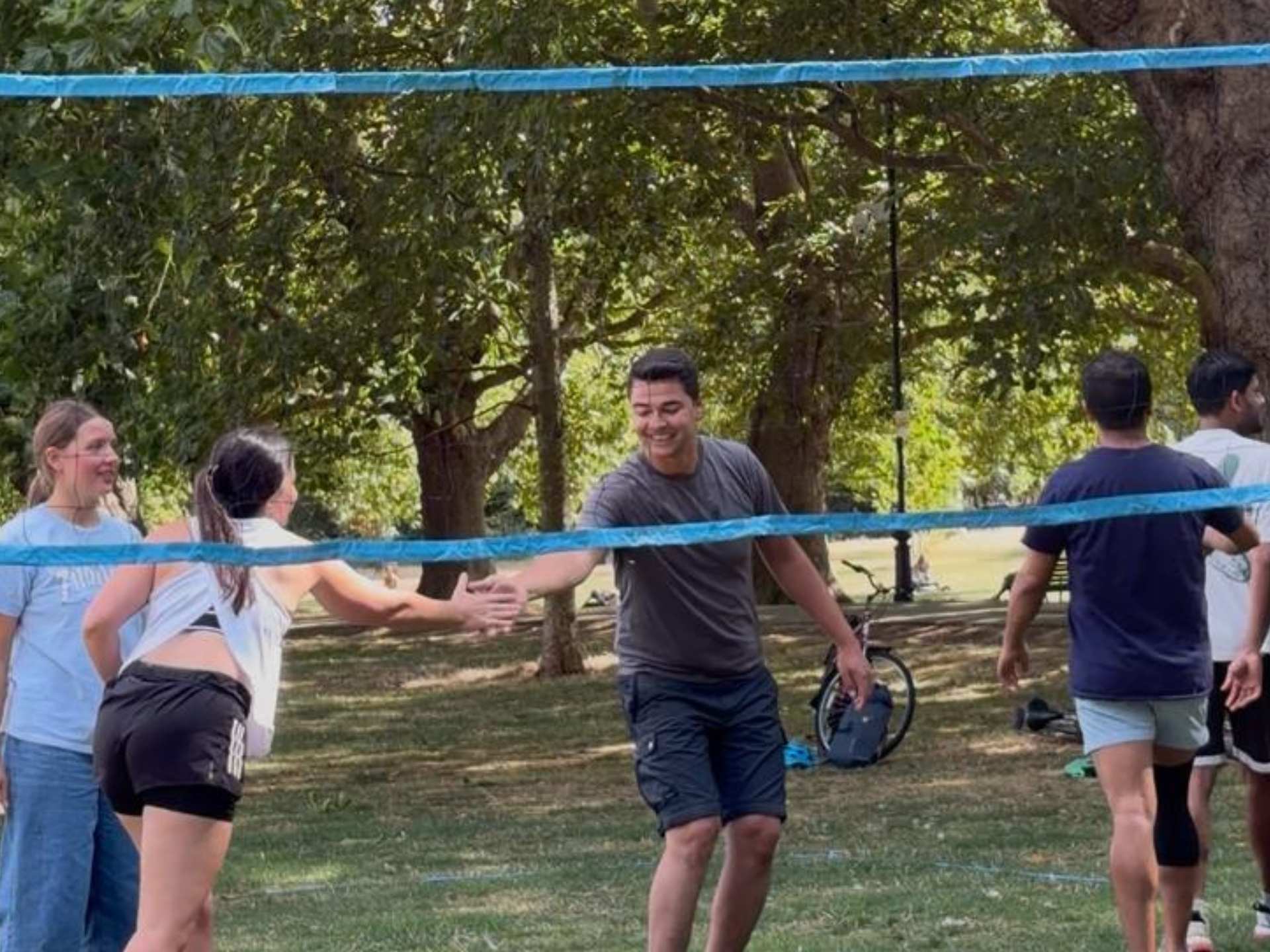 Players smiling and high-fiving over the net at a Social Sport volleyball session